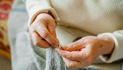 lähikuvassa neulovan vanhuksen kädet