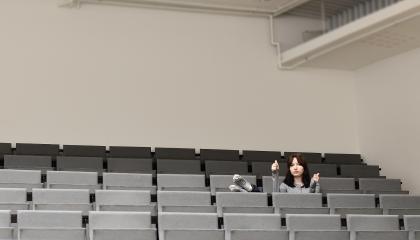 Henkilö istuu auditoriossa.