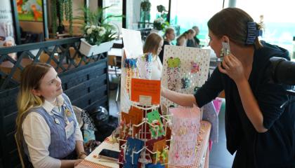 Livia Jokinen myy koruja ständillä. Asiakas kokeilee korvakoruja.