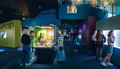 Paljon ihmisiä tutkimassa teoksia sinisävyisessa isossa, mutta tunnelmallsiessa  tilassa. 