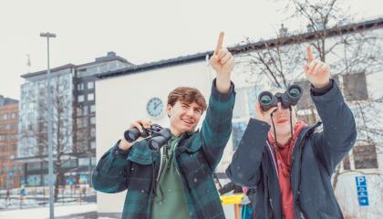 Klassillisen lukion opiskelijoita havainnoimassa koulun pihapiiriä kiikarein