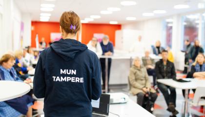 Mun Tampere -huppariin pukeutunut kaupungin työntekijä on yleisön edessä keskustelemassa heidän kanssaan.