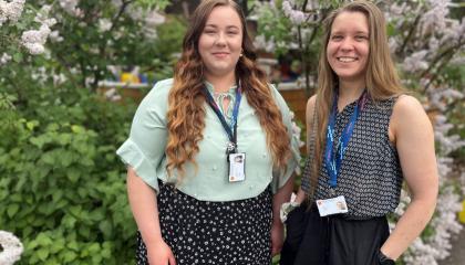 Ihmiset hymyilevät ja taustalla on kukkiva syreenipensas.