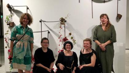 Viisi naishenkilöä poseeraavat iloisesti.