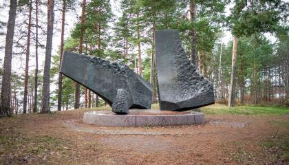 Puiden keskellä on kolme suurta metallilohkaretta.