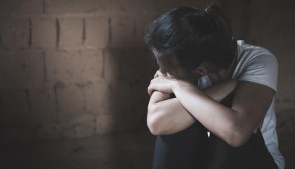 Ihminen katsoo pois kuvasta kohti tiiliseinää