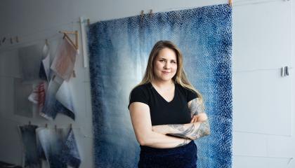 Nuori nainen seisoon sinisävyisen teoksen edessä. 