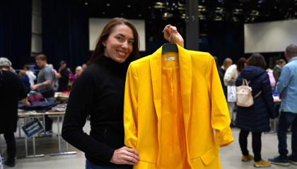 Nainen esittelee keltaista jakkua vaatteidenvaihtotapahtumassa.