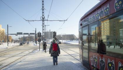 Ihmisiä ja kissakuvioinen raitiovaunu talviaikaan.