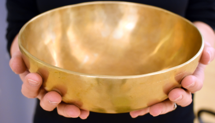 Kädet pitelevät tyhjää äänimaljaa.