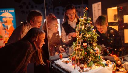 Nuoret tutkivat ihailevasti joulukuusiaiheista kuvaelmaa. 