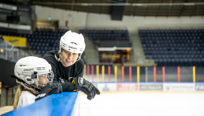 Äiti ja tytär katsovat toisiaan luistelukentän laidalla Hakametsän hallissa.