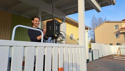Tutkija asentamassa mittalaitteita päiväkodin kuistilla.