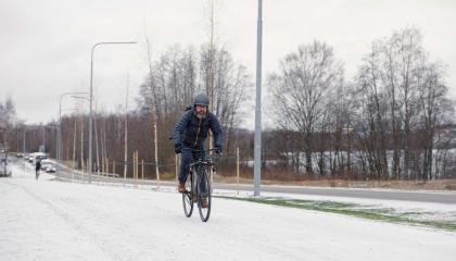 Pyöräilijä pyöräilemässä pyörätiellä talvella.