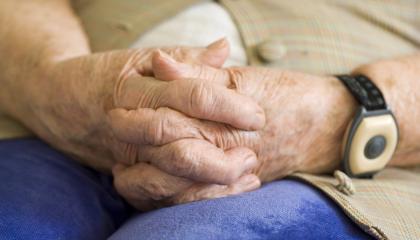 Lähikuva iäkkään ihmisen käsistä, jotka ovat sormet ristissä.