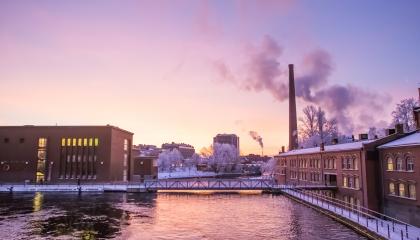 Talvinen Tammerkoskinäkymä auringonnousun aikaan, jolloin aurinko punertaa taivaanrannassa.