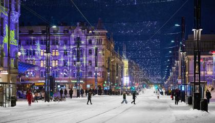 Ihmiset ylittävät lumista Hämeenkatua. Taustalla valaistuja rakennuksia.