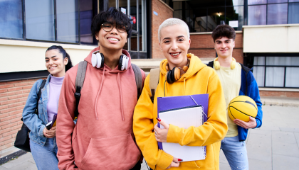 Neljä rennosti pukeutunutta nuorta koulun pihalla.