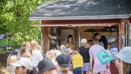 Henkilöt jakavat kopissa ruokaa ja kopin edessä on jono lapsia.