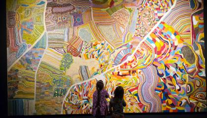 Kaksi lasta katselee isoa ja värikästä maalausta.