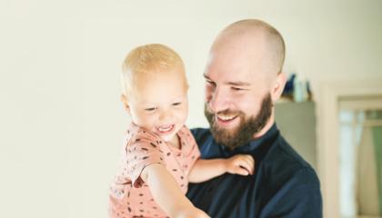 Isä pitää lasta sylissä.