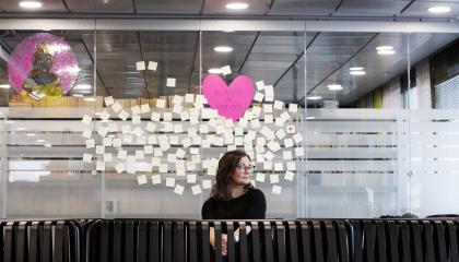 nainen keskellä kuvaa, taustalla lappuja.