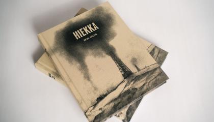 Eeva Meltion Hiekka-sarjakuva-albumeita kasassa. Kirjassa ruskean-musta kansi.