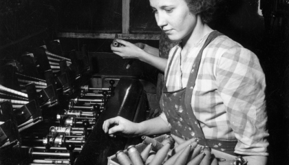 Henkilö istuu kudontalaitteen äärellä. Vanha valokuva.