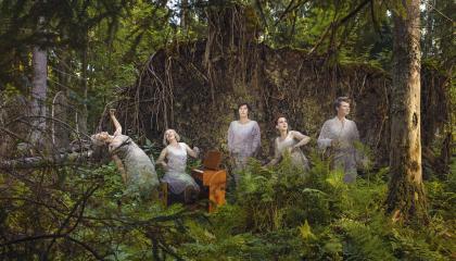 Ihmisiä soittimineen metsässä.