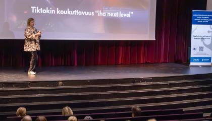 Tilaisuuden puhuja seisoo esiintymislavalla pitämässä koulutusta.