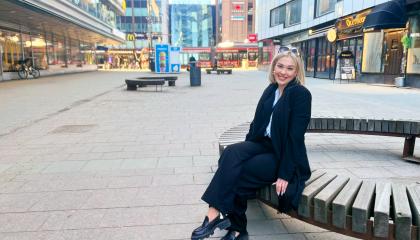 Henkilö istuu penkillä Tuomiokirkonkadulla Tampereella.