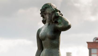 Wäinö Aaltosen Suomen neito-patsas vyötäröstä ylöspäin harmaata taivasta vasten.