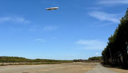 Ilmalaiva lentää peltoaukion yllä. 
