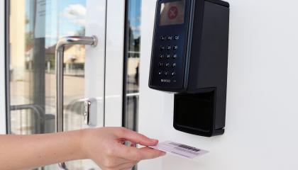 Asiakas pitää kirjastokorttia omatoimikirjaston lukijassa. 