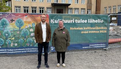 Jaani Haapasalo ja Annamaija Saarela seisovat ulkovaatteissa Nekalan kulttuurikeskuksen työmaan edessä. Taustalla lakana, jossa lukee &quot;Kulttuuri tulee lähelle&quot;.