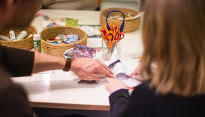 Kuvassa aikuinen ohjaa lasta askartelussa