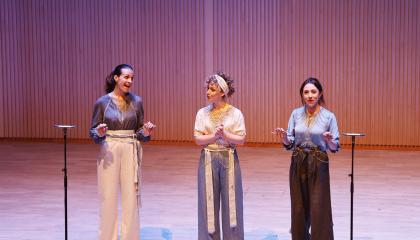 Kolmen naisen lauluyhtye laulaa lavalla.