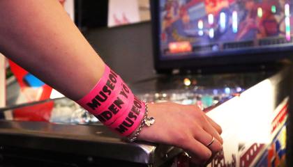 Ranteessa pinkit Museoiden yö -rannekkeet, käsi pelikoneen päällä.