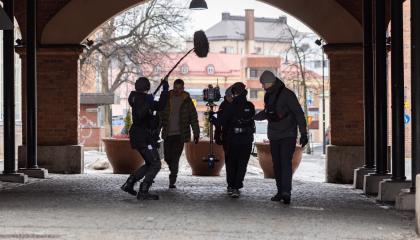 Elokuvan kuvausryhmä kävelee tunnelissa, kaupunki piirtyy taustalla.