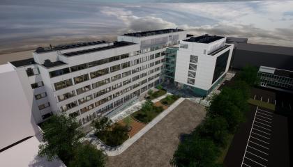 Havainnekuvana ilmakuva, jossa on valkoinen kaksiosainen rakennus. Rakennuksen edessä sisäpiha ja sora-alue.