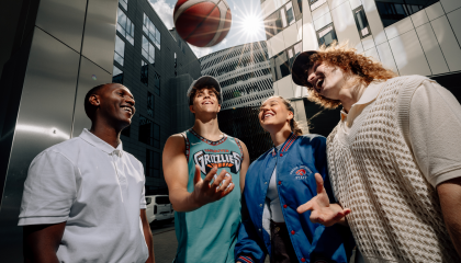 Four cheerful young people with a basketball outside the Nokia Arena.