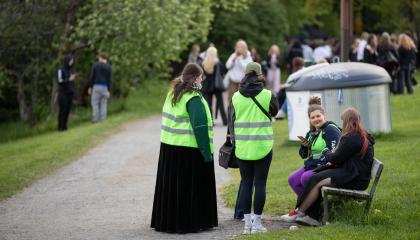 Vihreäliiviset jalkautuvat nuoriso-ohjaajat juttelevat nuoren kanssa puistossa penkin ympärillä