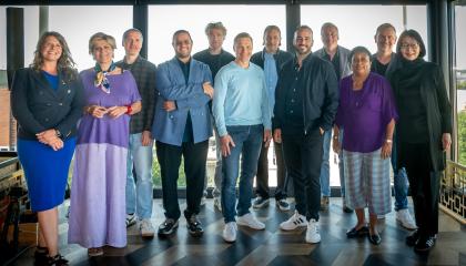 Tuomaristo poseeraa kameralle kuvausseinän edessä.