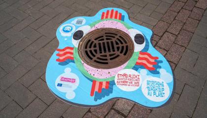 Värikäs ahventarra katukaivon kannessa.