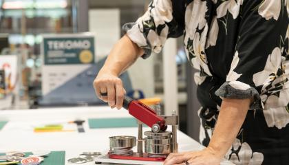 Henkilö käyttää yhteiskäyttöistä pinssikonetta.