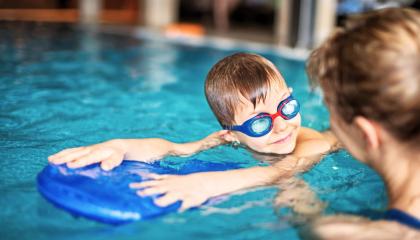 Pieni poika harjoittelee uimista uimalaudan avulla.