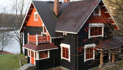 Hirsitalo, jossa on kaksi kuistia. Taustalla on järvi.