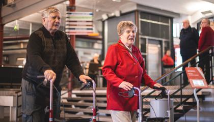 Mies ja nainen kävelevät rollaattoreista tukea ottaen.