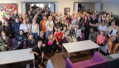 kuvassa iso joukko nuorisopalveluiden työntekijöitä. Osa istuu sohvilla ja osaa seisoo