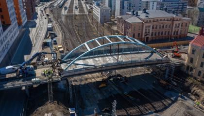 Kuvassa vaaleansininen silta radan päällä ja työkoneita,